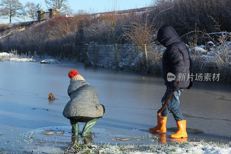 两个男孩在结冰的水坑上玩