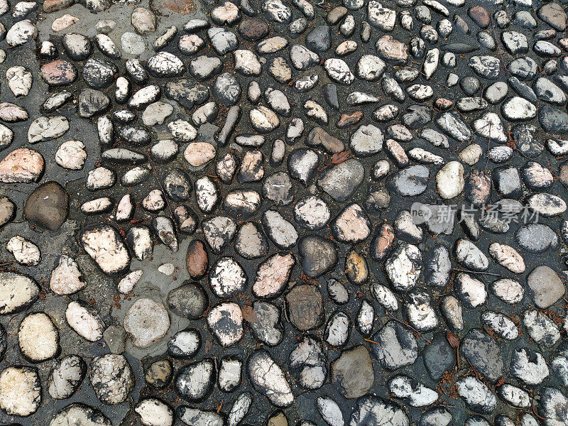 铺路石:由类似大理石的圆形轻石制成的铺路石波斯尼亚和黑塞哥维那萨拉热窝老城的铺好的广场。雨后又湿又亮的漂亮石头。自然光下的特写