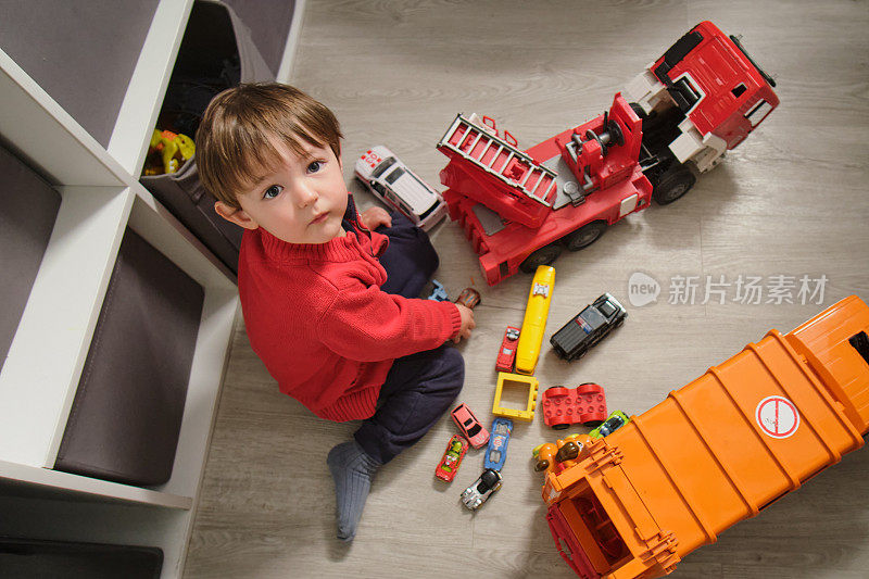 这个爱玩的孩子喜欢推着他的玩具汽车在房间里转。