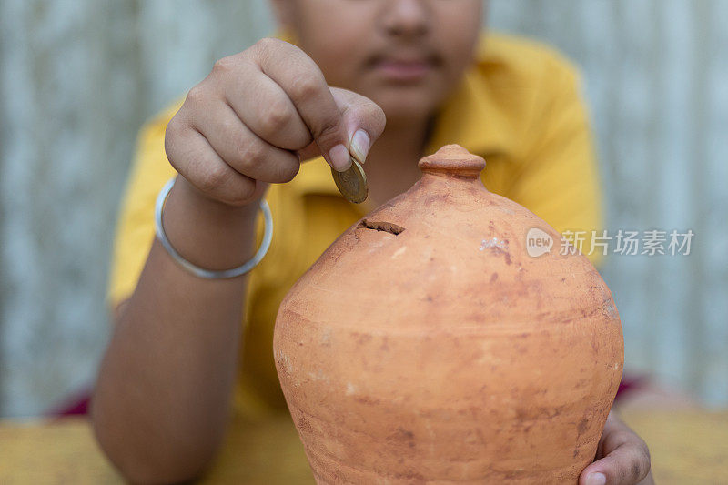 一幅印度小孩把硬币放进硬币堆的肖像