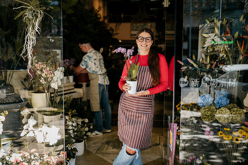 年轻漂亮的女人在她的花店里