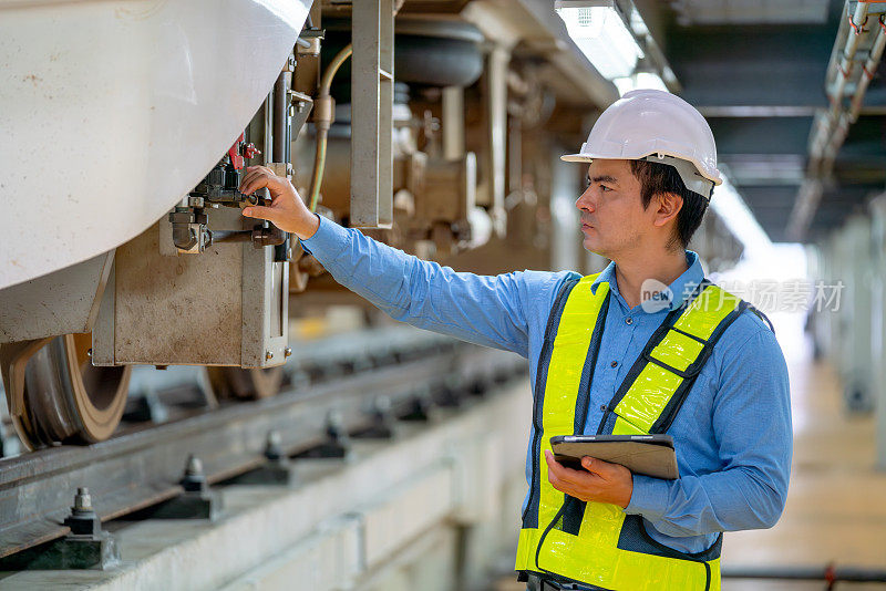 专业工程师在工厂工作场所拿着平板电脑检查或维护部分电气或地铁设备。