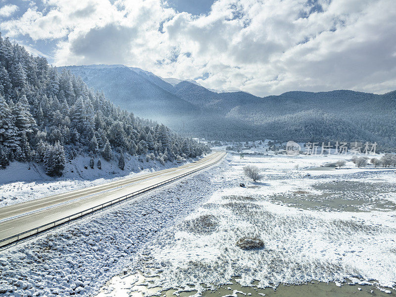 冬天结冰的湖泊和雪山之间的高速公路