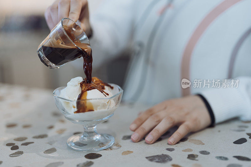 把浓咖啡冰淇淋倒进杯子里的女人。