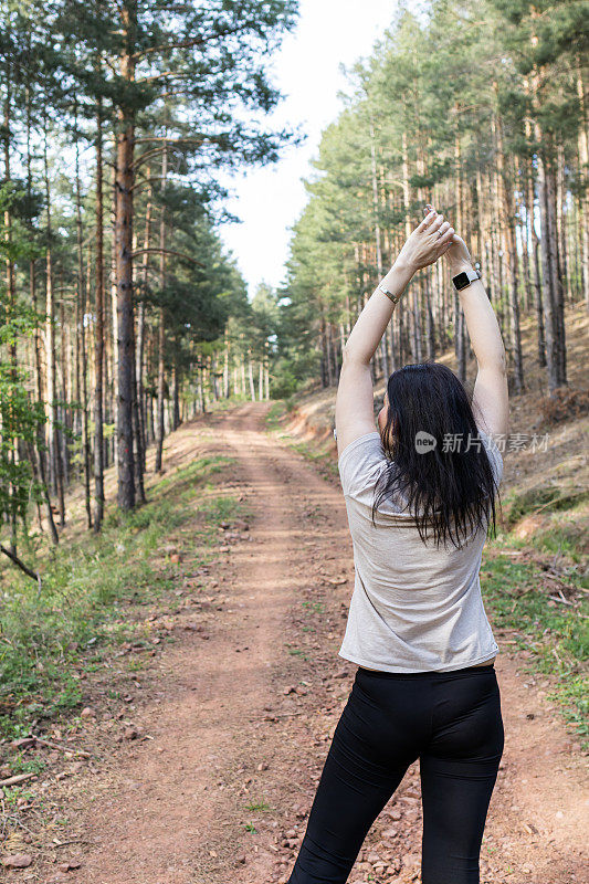 快乐的女跑步者正在森林里阳光明媚的小路上享受慢跑或越野跑。