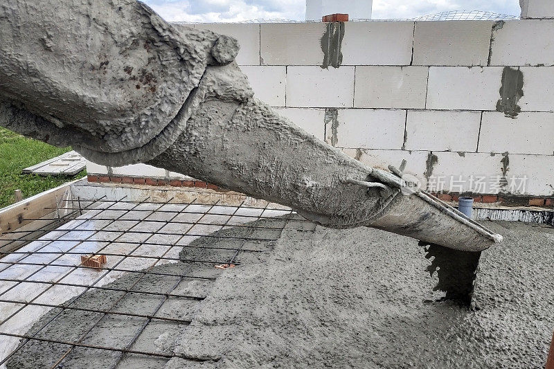 混凝土搅拌机通过排水沟向混凝土板注入水泥，下水道管道清晰可见。