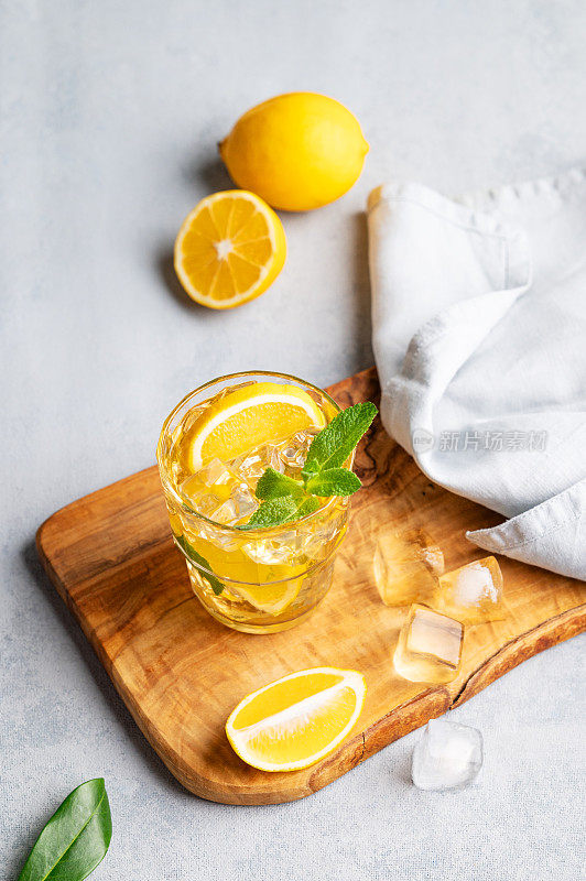 冰茶加柠檬和薄荷，放在木板上，背景是浅色的柑橘类水果。
