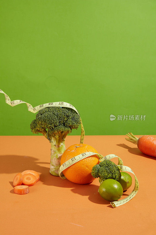 蔬菜和水果分类框架显示在橙色餐桌厨房与绿色背景。素食健康食品概念模板，复制空间与正面视图