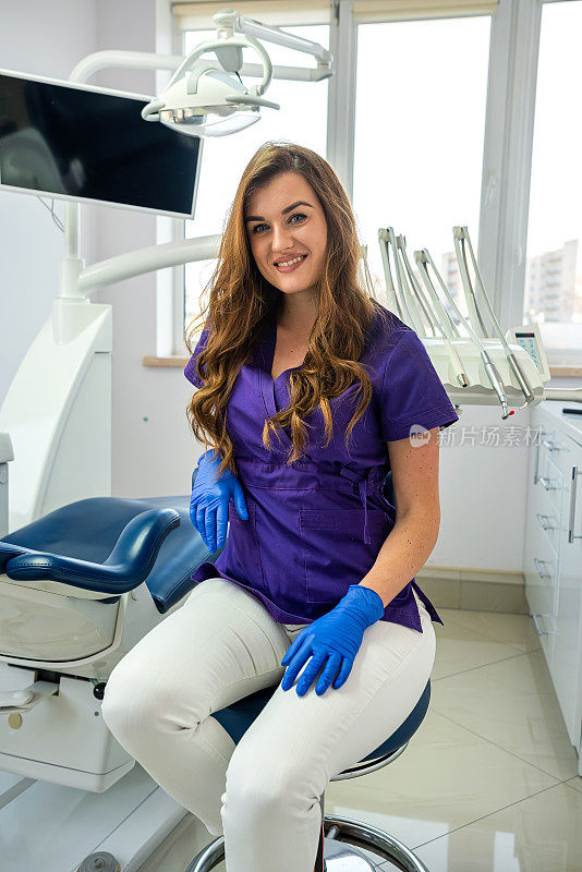 年轻的女牙医在制服和保护手套的位置单独在诊所