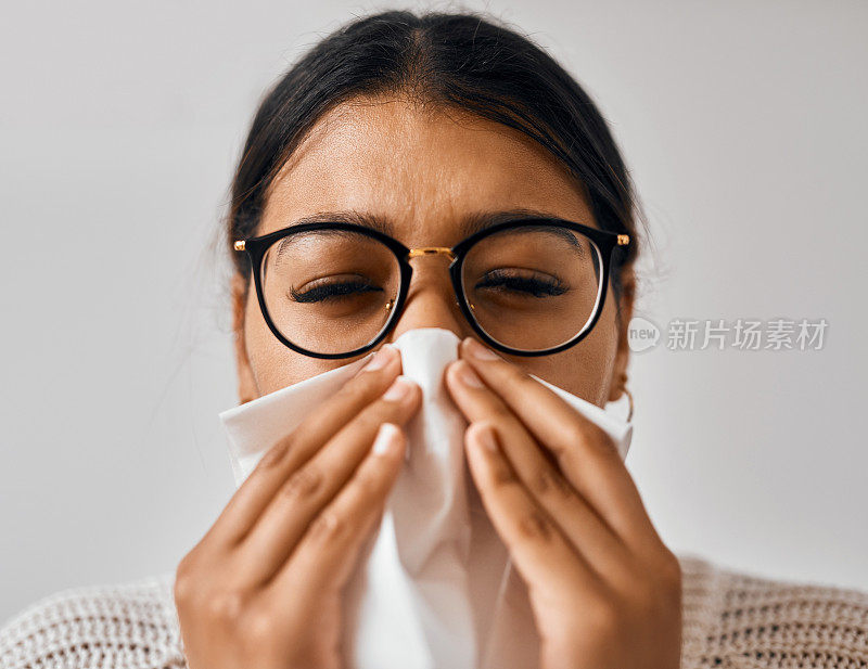 一名年轻女子在家养病时擤鼻涕的照片