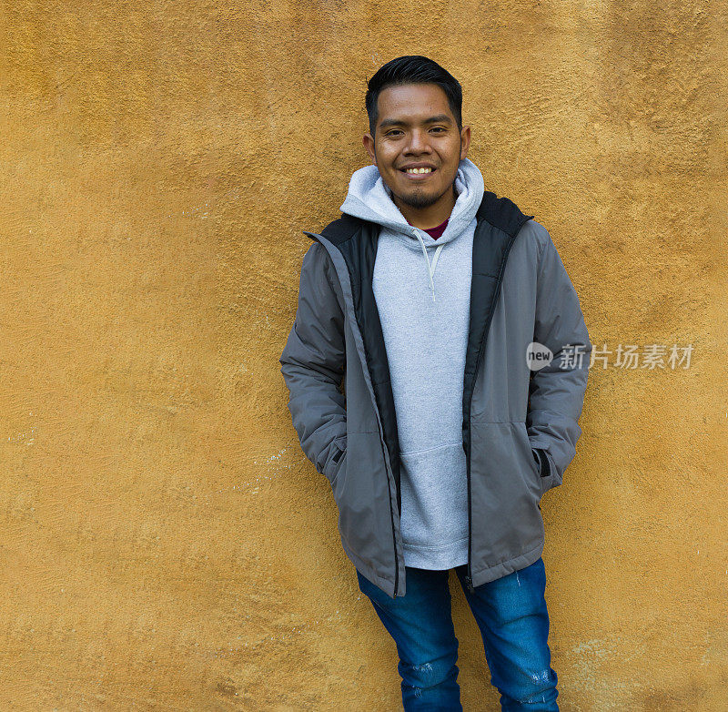 一个墨西哥种族的动画男子站在一堵黄色的墙前微笑。