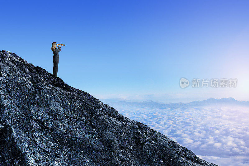 站在山顶的女人用望远镜眺望远方