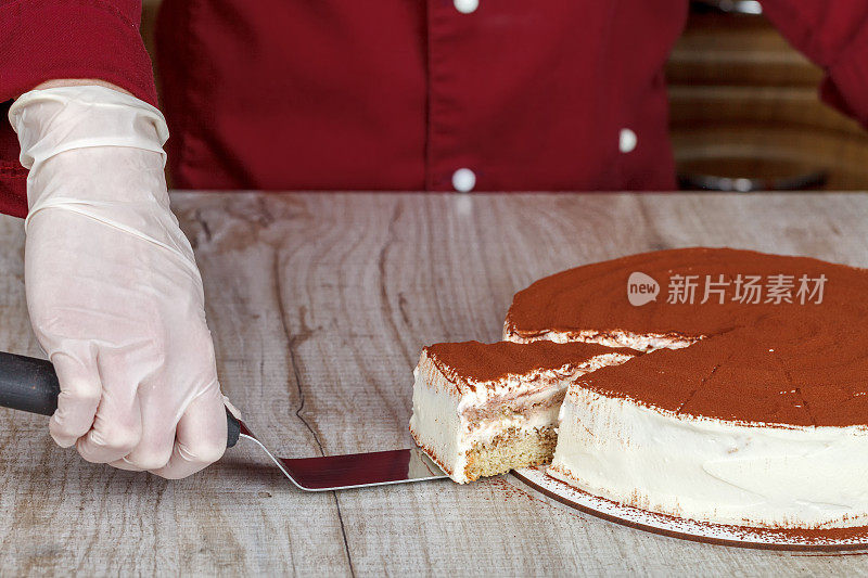 提拉米苏蛋糕与切与一片和刀刃上的灰色背景，特写