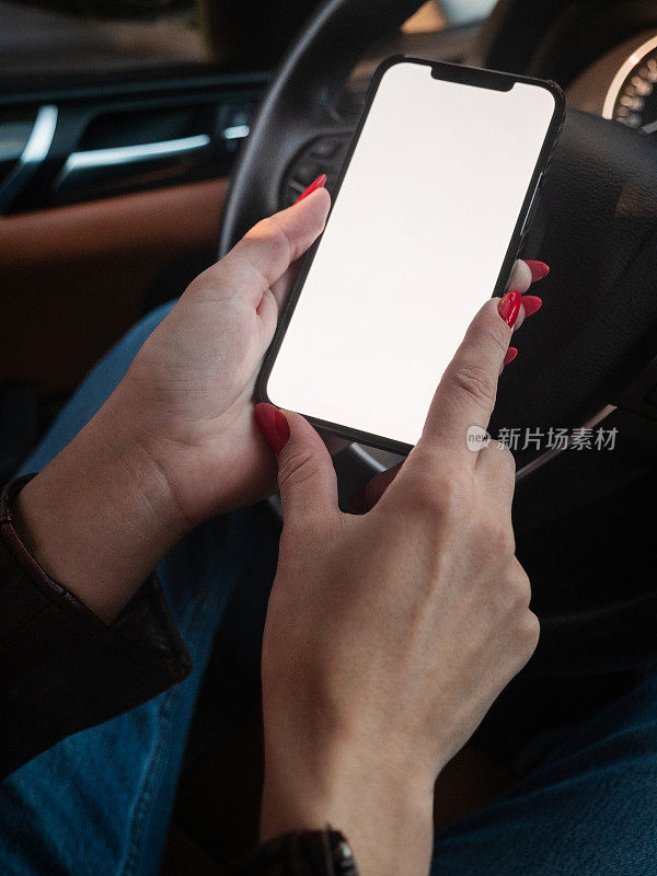 一个女人在车上用黑屏智能手机