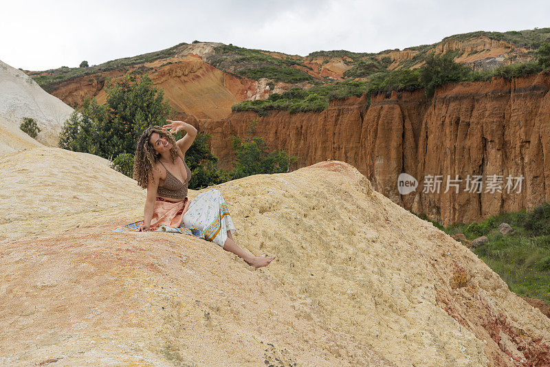 一位拉丁女子坐在沙漠中的山上享受大自然