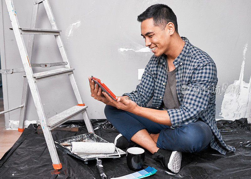 一名年轻的亚洲男子在装修时观看DIY视频创意和操作指南