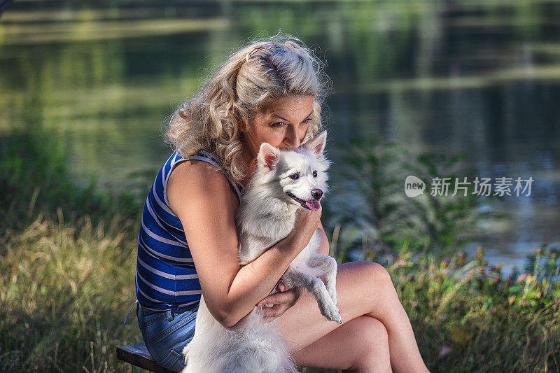 一个女人在湖边和宠物狗一起享受时光