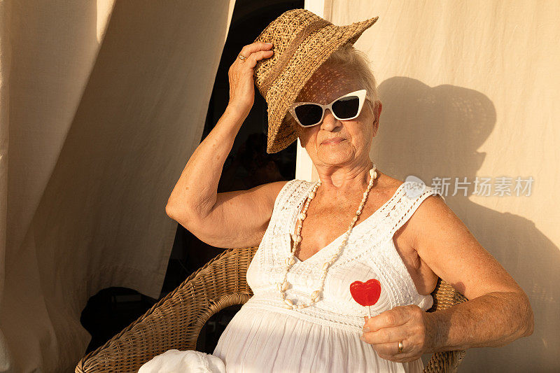 头发花白的白种老妇人，拿着棒棒糖，戴着墨镜。80岁的女人。