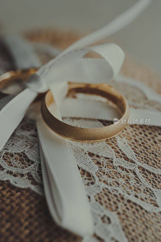 垂直选择聚焦镜头的金婚戒指在白色丝带上的花边携带者枕头