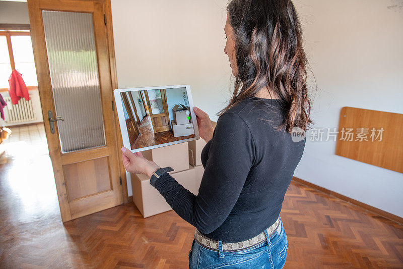 一名女子计划出售她的空公寓，用她的智能平板电脑拍摄自定义设计客厅的室内。卖房子的人带着视频参观她的家