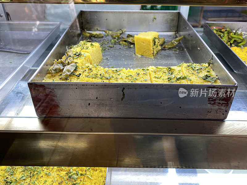 印度商店陈列的Khandvi(辣克面粉卷)的托盘图像，高架视图，关注前景