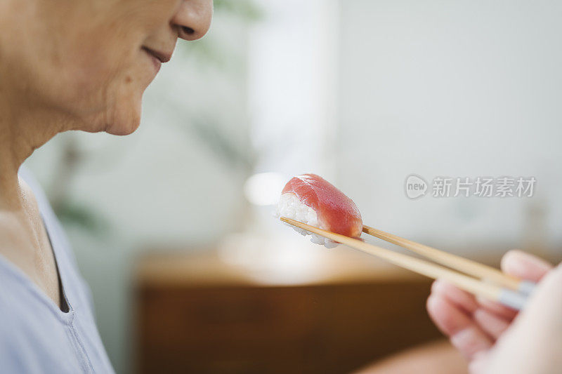 亚洲老年妇女吃寿司的手