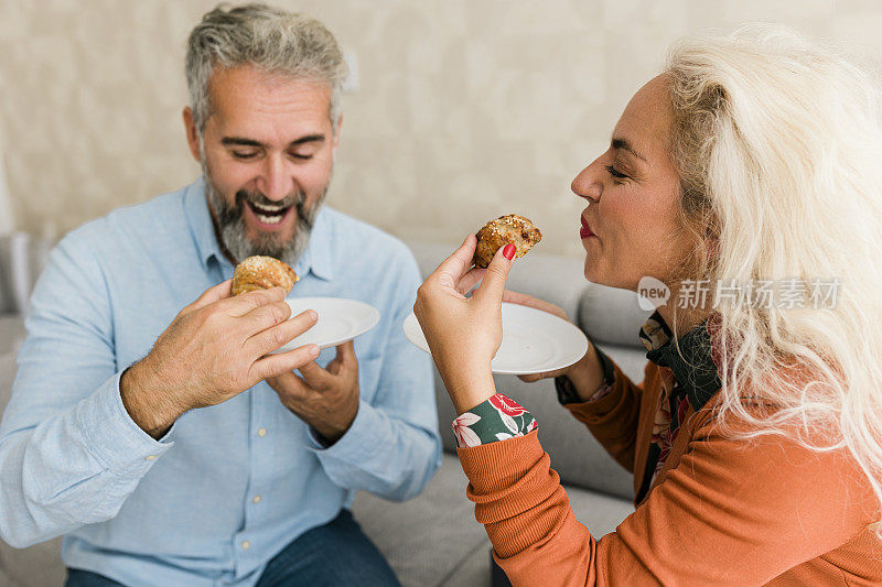 一对夫妇坐在客厅里一起吃着自制的糕点