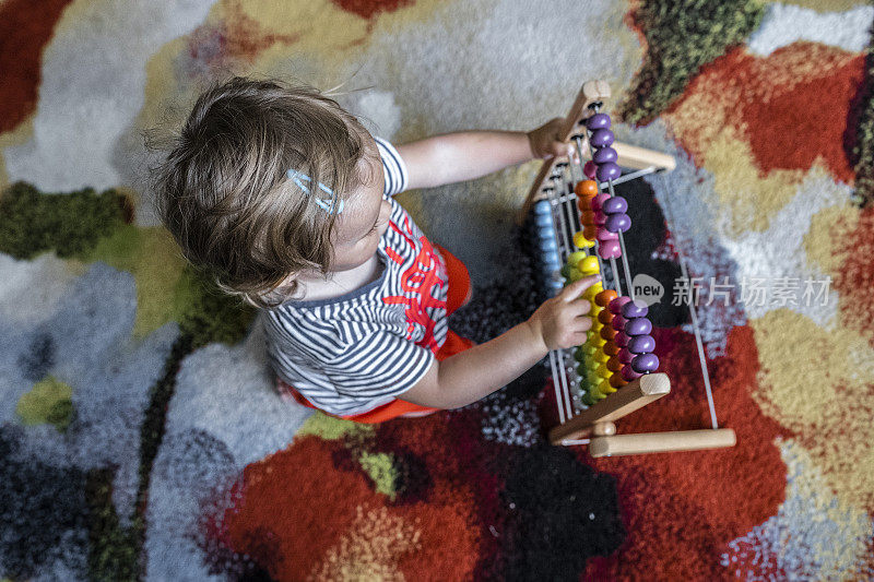 宝宝在家里玩彩色的木制算盘玩具。