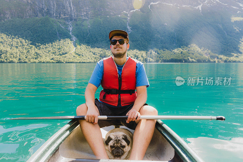 一名男子和狗在挪威风景秀丽的洛瓦特内特湖划独木舟的正面视图