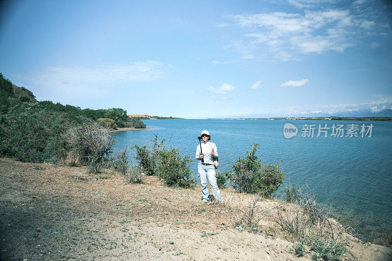 女游客在湖岸拍视频