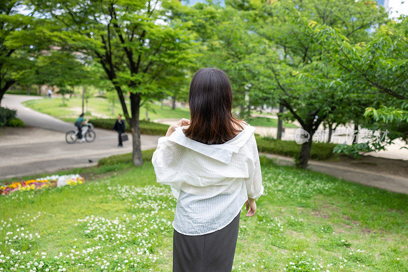 年轻女子在公园散步的后视图