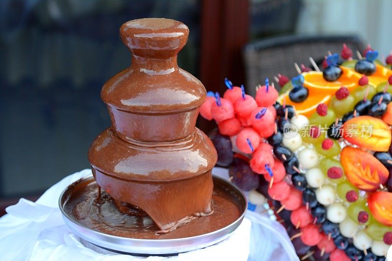 巧克力喷泉和玻璃桌上不同水果的雕刻