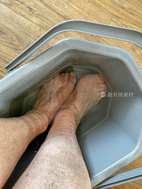 男人把脚泡在一桶热水里