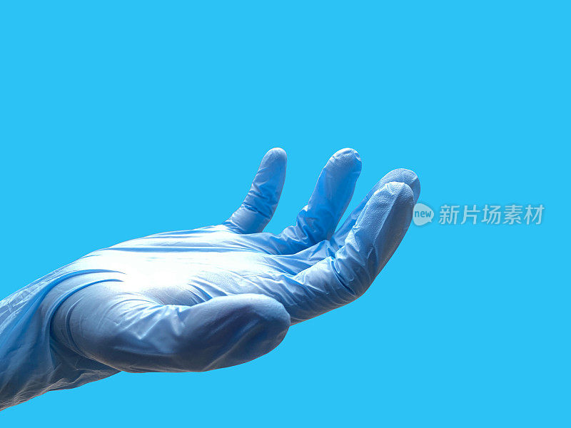 医生的手戴着手术手套。在蓝色背景上，带手术手套的手张开，并留有复制空间