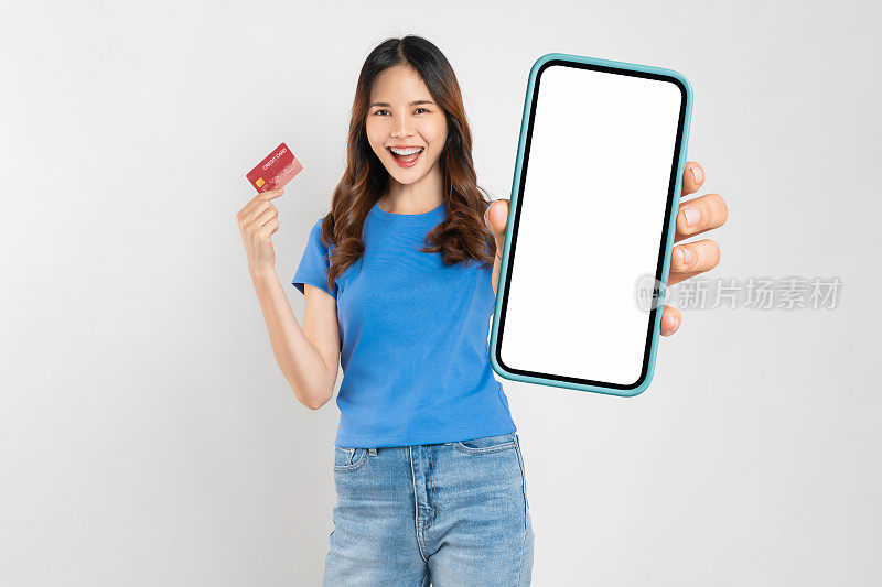 美丽的亚洲女人拿着空白屏幕和白色背景信用卡的智能手机模型。