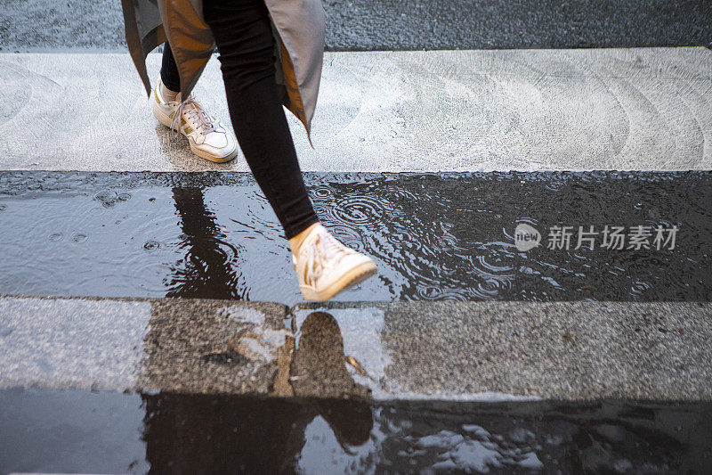 雨中走过斑马线的人