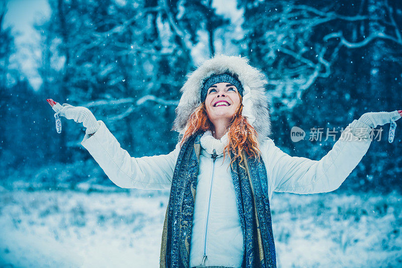 幸福的女人在冬天森林附近的白雪皑皑的草地