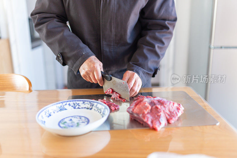 一位老人在餐厅切牛肉