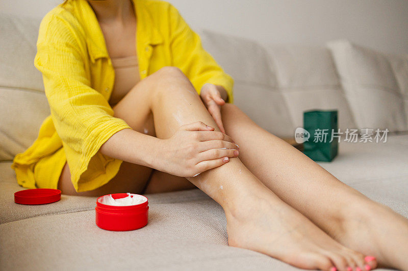 一个无法辨认的女人小心地在腿上涂抹护肤霜，特写