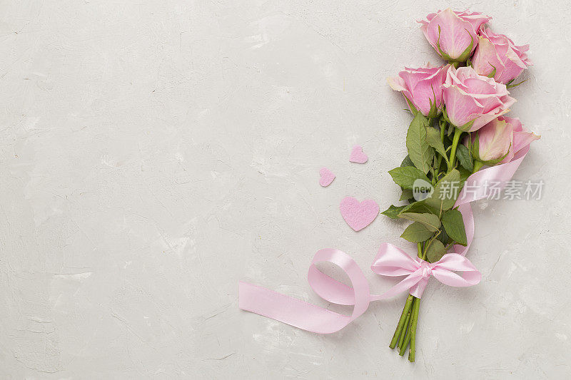 粉红色玫瑰与心在混凝土背景，俯视图。情人节概念