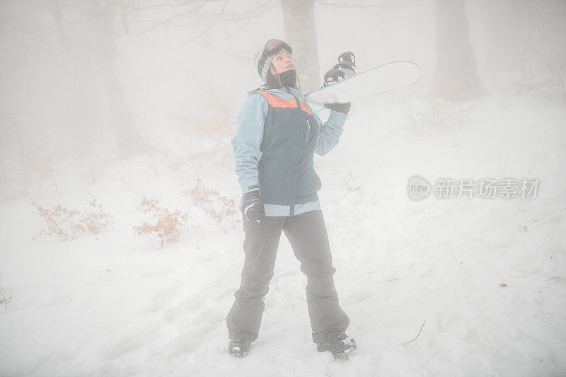 一个女子单板滑雪运动员准备在山上滑雪的全长视图