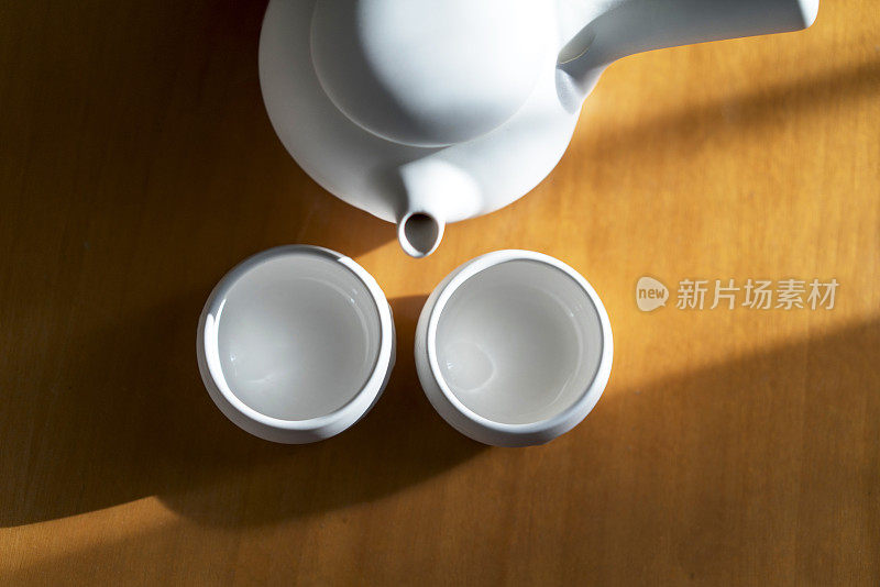 陶器茶壶和杯子在阳光下的桌子上