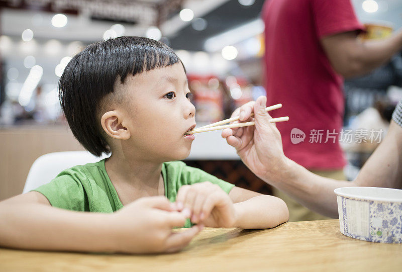 快乐的亚洲孩子用筷子吃美味的面条