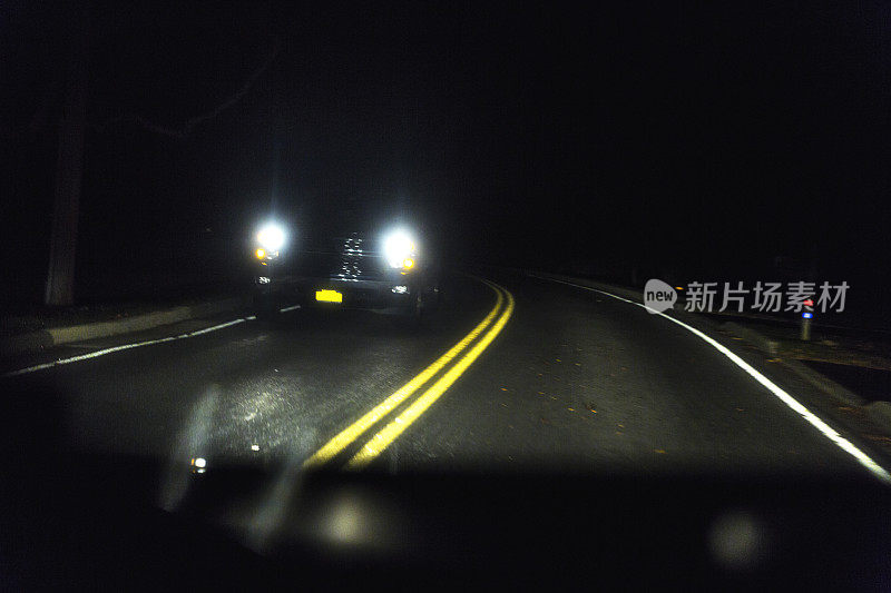 乡村夜间公路弯道上接近车辆的前灯