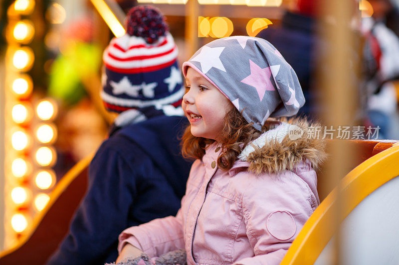 小男孩和小女孩，兄弟姐妹在圣诞市场的旋转木马上