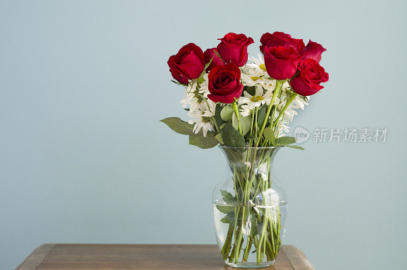 桌上的花瓶里放着玫瑰和雏菊