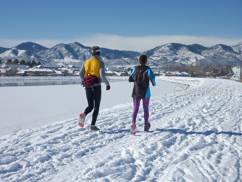 跑步者在科罗拉多州的湖与落基山脉的雪