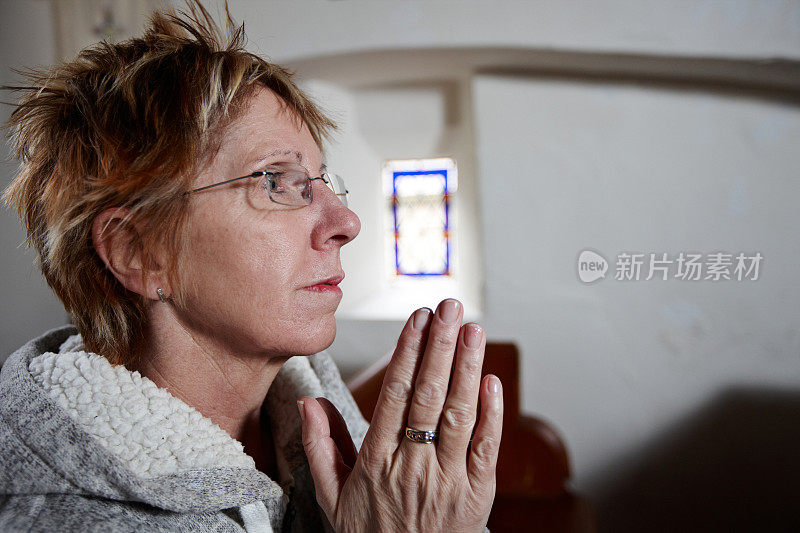 成熟的金发女人在教堂祈祷