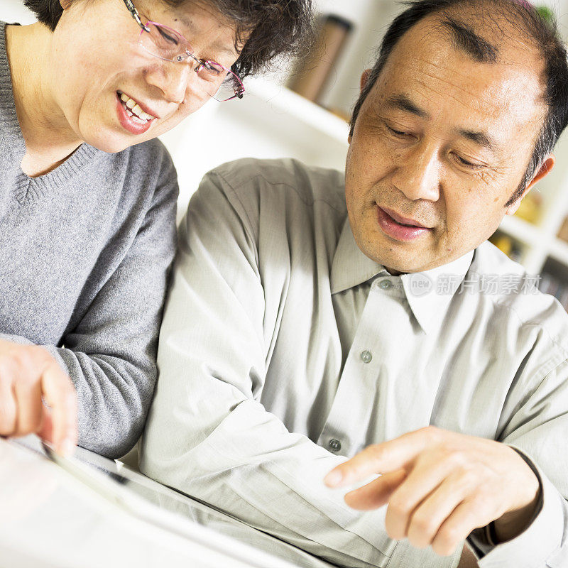 一对亚洲老年夫妇一起用平板电脑