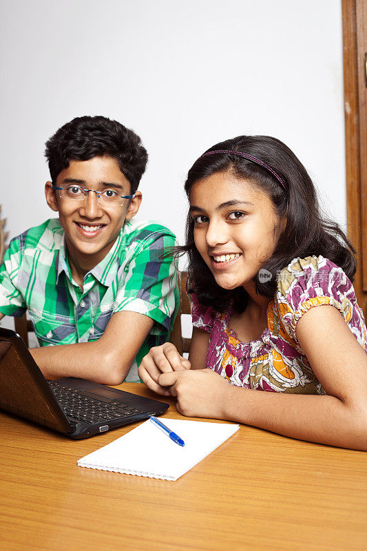 兴高采烈的印度少年弟弟妹妹用笔记本电脑做作业